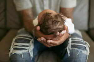 Close-up of father holding baby girl while sitting on sofa at home